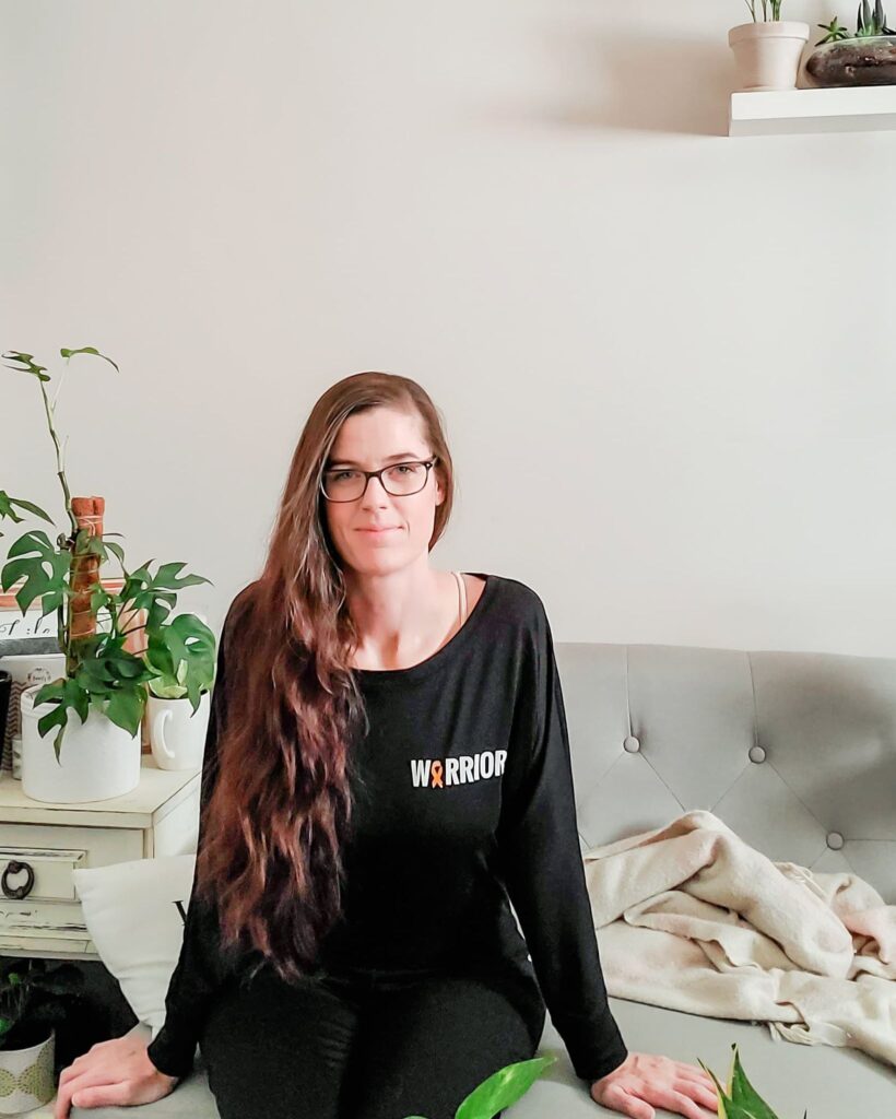 sandra, a woman with endometriosis, is wearing a shirt with the word "warrior" and a yellow ribbon on it