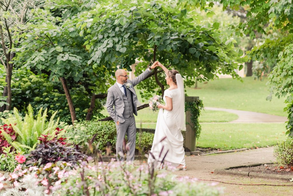 a groom twirls a bride in the gardens at Ivey Park. Photo included in a wedding photography education blog post about the importance of contracts.