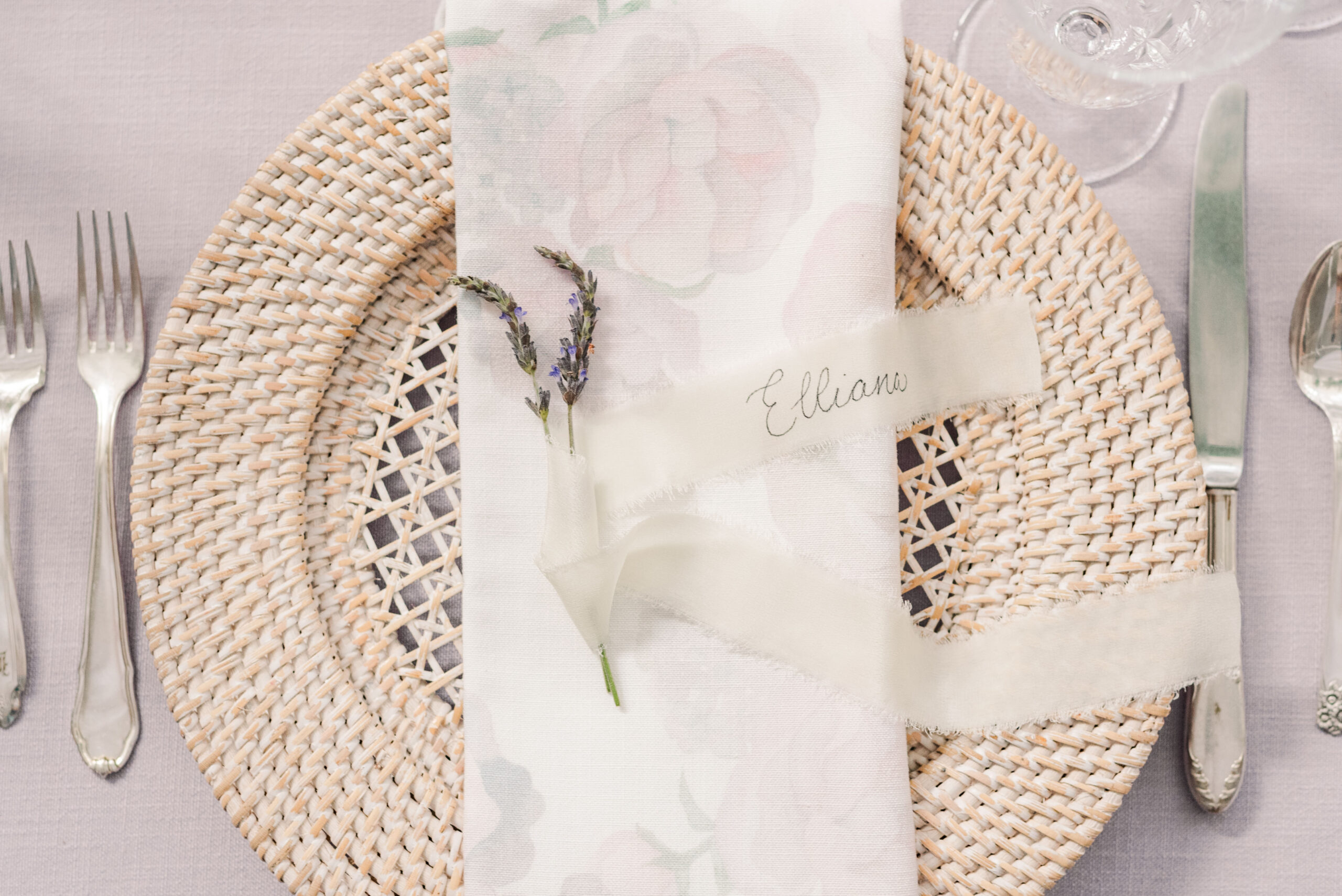 a sprig of lavender sits on top of a white linen napkin, and the napkin rests on a wicker table charger. the photo is used in a blog post about pic-time galleries