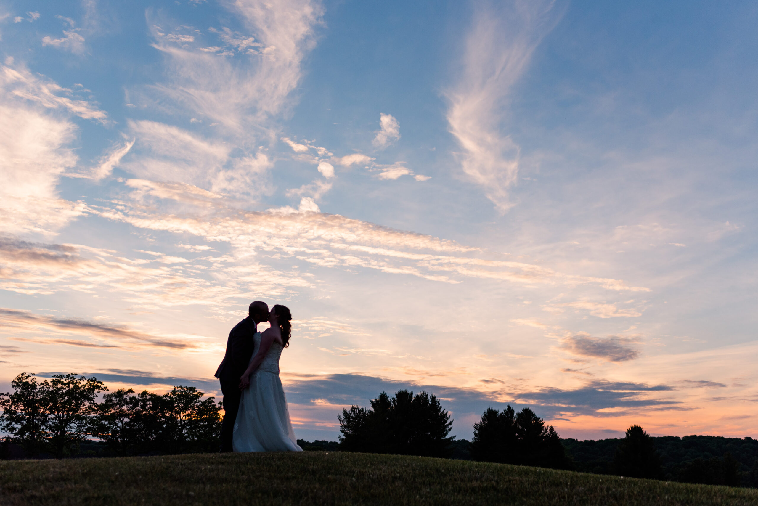 a silhouette of a bride and groom kissing in front of a sky at sunset. used in a blog post about honeybook and pic-time's new integration.
