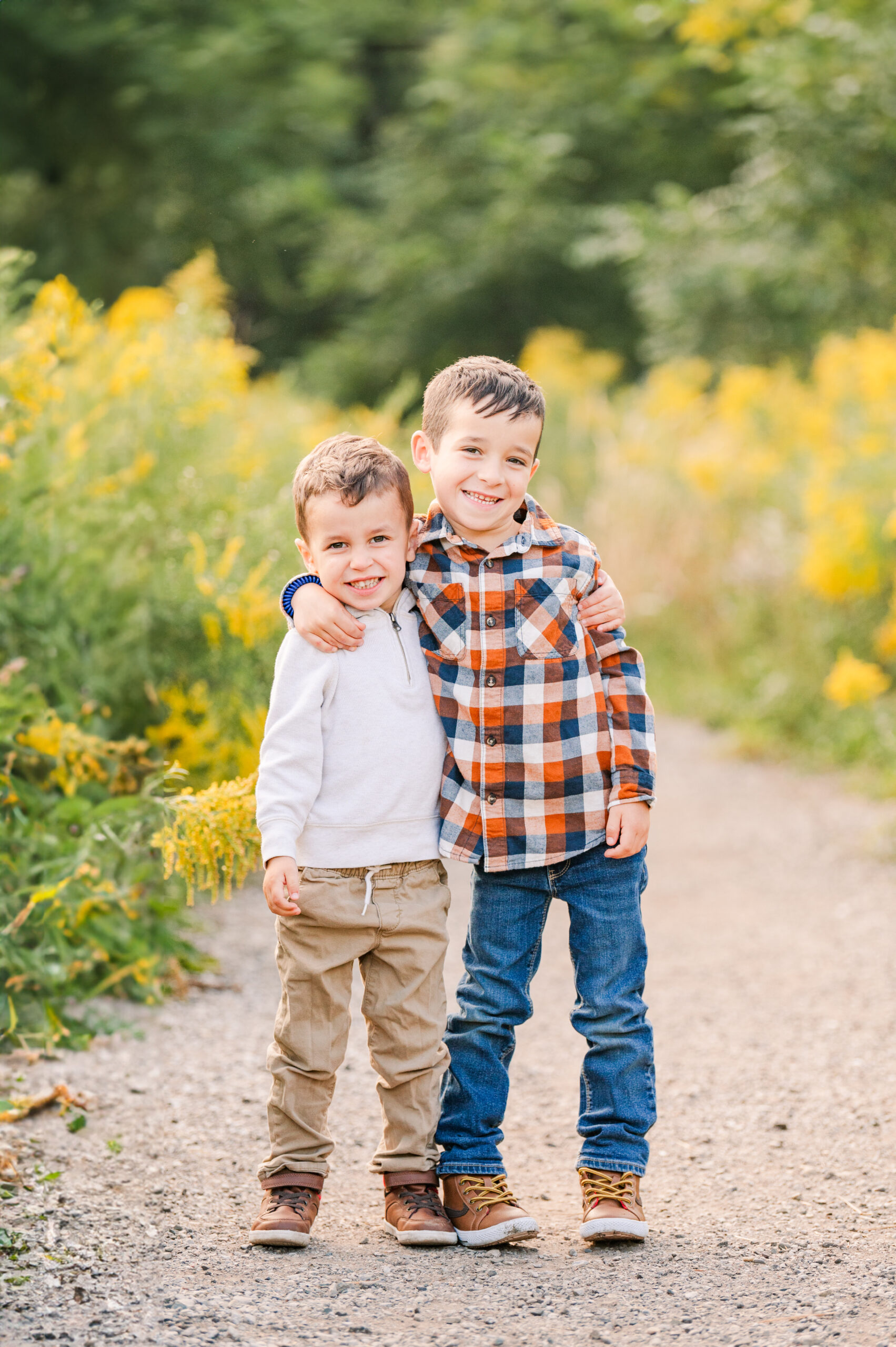 two brothers stand with their arms around each other, smiling at the camera during a family session by life is beautiful photography