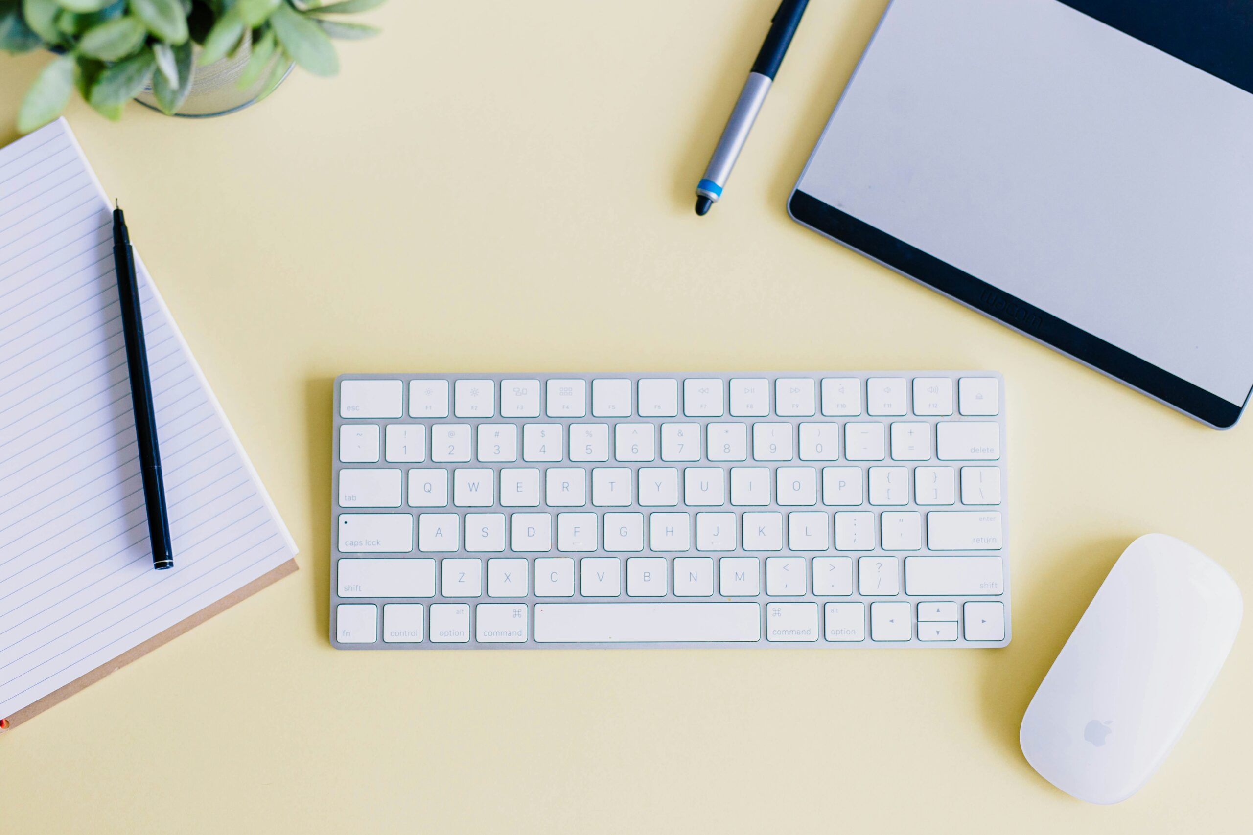 A keyboard and notebook laying on a yellow desk. Used in a blog post about photography burnout