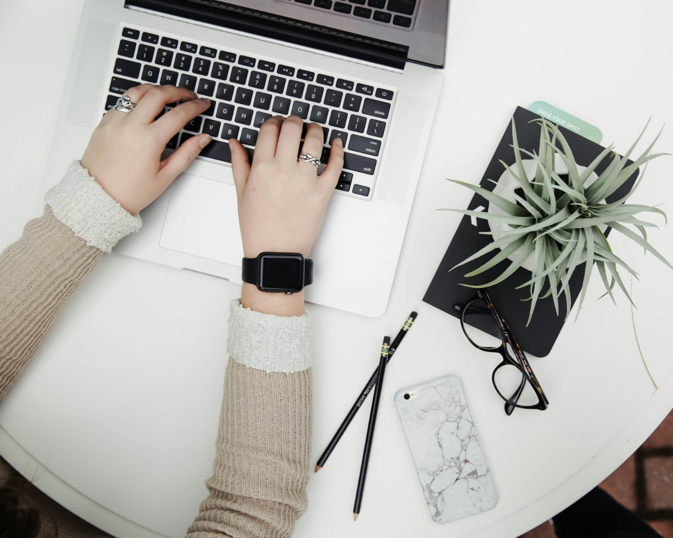 A caucasian woman types on a laptop with a plant beside her. Used in a blog post about Honeybook Pipeline Setups